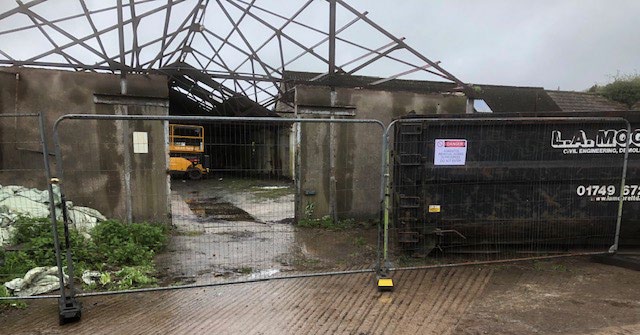 Barn structure behind secured site fencing at Court Farm