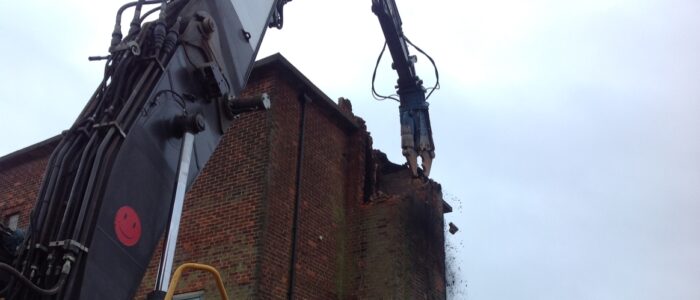 Shear attachment on the high reach crane begins to demolish the building